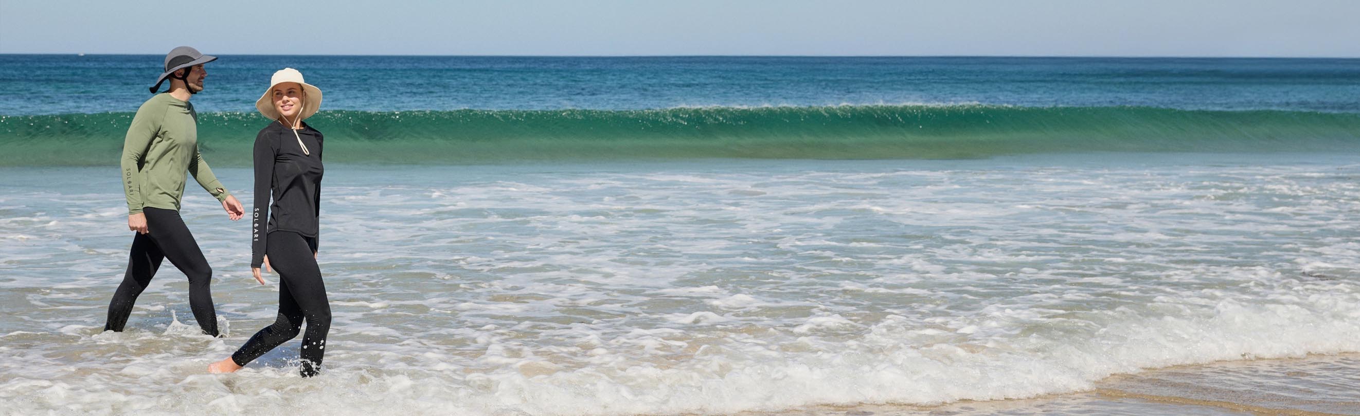 Two people walking on a beach with waves in the background