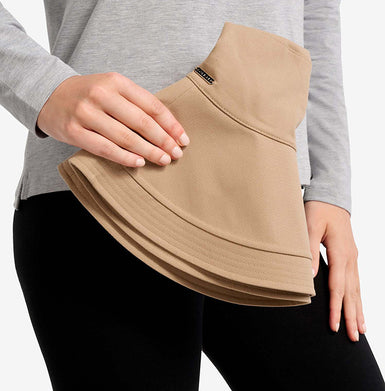 Person holding a beige solbari sun hat with a grey top and black pants on a white background